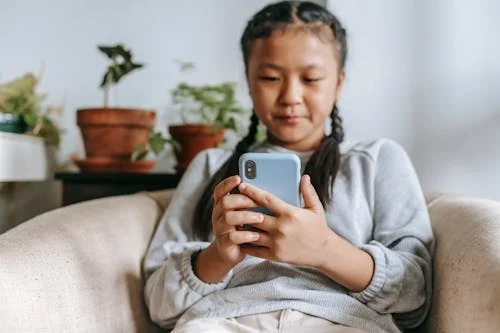 A young girl using a smartphone, symbolizing real-world interactions with AI tools and the growing impact of LLMs on everyday brand discovery.